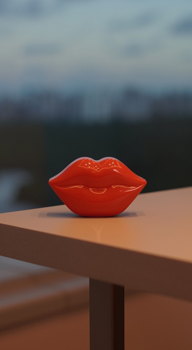 Uma boca de louça vermelha brilhante sobre a mesa, com o mar desfocado ao fundo em luz de fim de tarde.