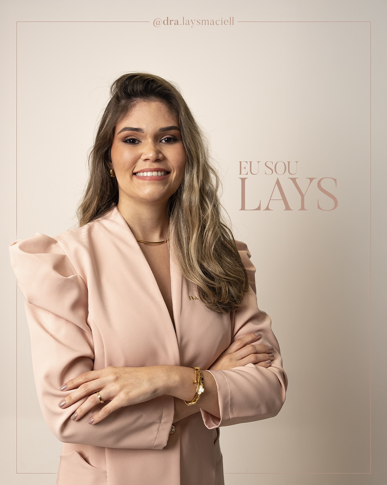 Lays Maciel de blazer rosa, braços cruzados, sobre fundo bege com a arte escrita EU SOU LAYS.